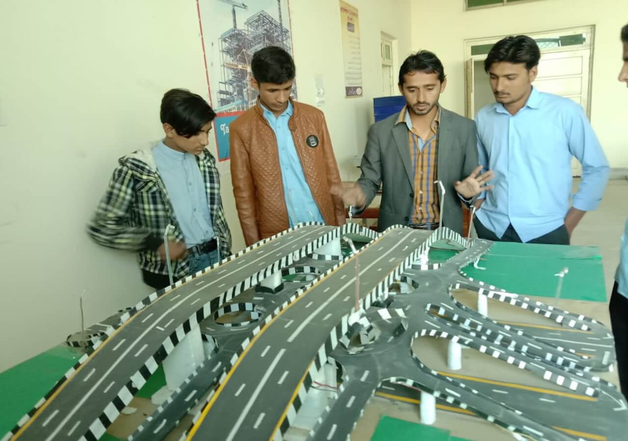 Front view of a historic university building with a prominent statue under a clear sky.